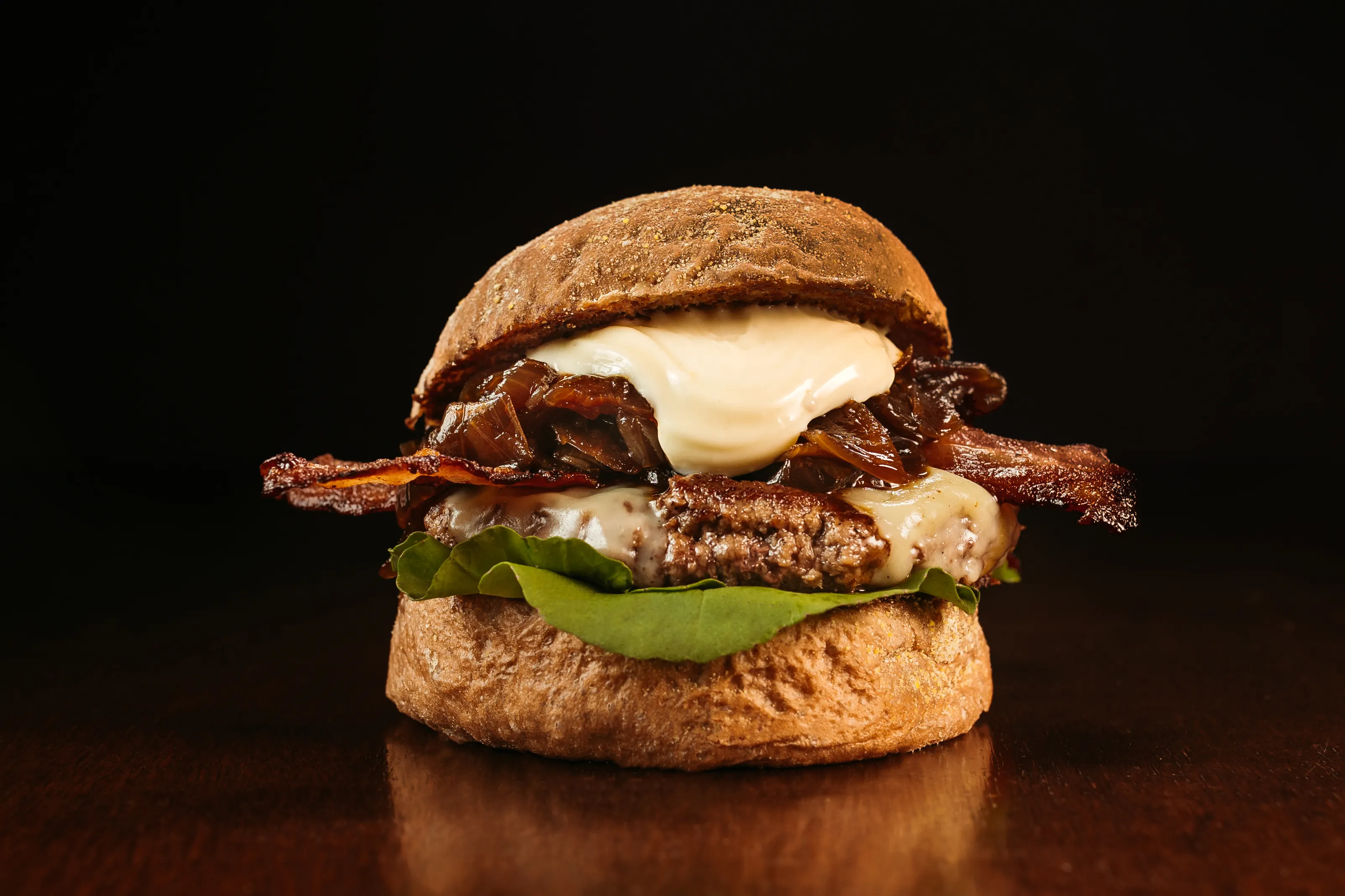 A close-up of a richly layered dish with melted cheese, caramelized onions, and fresh herbs, set against a dark, warm background that evokes a cozy kitchen table.